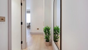 A hallway with a large mirror, a potted plant, and a door leading to another room. - The Mezzanine Studio at Bramham (London)