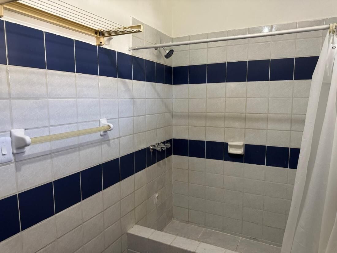 A shower area with blue and white tiles, a white towel rack, and a shower curtain.