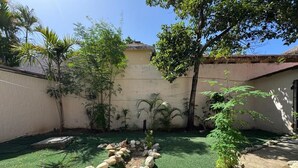 A garden with a stone pathway, green grass, and various plants. - Cozy Studio Apartment 2 min to the Beach, Rooftop (Sosúa)