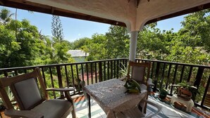 A balcony with a table and chairs, surrounded by potted plants and a railing. - Cozy Studio Apartment 2 min to the Beach, Rooftop (Sosúa)