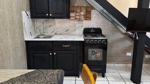 A compact kitchen with black cabinets, a marble countertop, a gas stove, and a built-in oven. - Cozy Studio Apartment 2 min to the Beach, Rooftop (Sosúa)