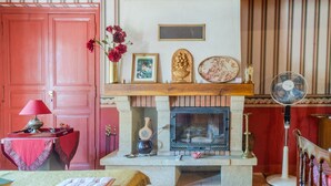 A room with a fireplace, a red door, a table with a lamp, and a fan. - Holiday Home 'Des Tilleuls' with Private Garden (Saint-Mathieu)