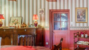 A room with striped wallpaper, a wooden ceiling, a red door, a table with a lamp, and a framed picture. - Holiday Home 'Des Tilleuls' with Private Garden (Saint-Mathieu)