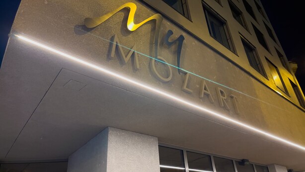 Un edificio con il cartello illuminato 'MY MALLART' di notte.