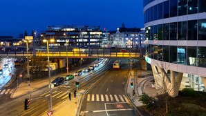 Un complesso viadotto con veicoli, attraversamenti pedonali e edifici illuminati.