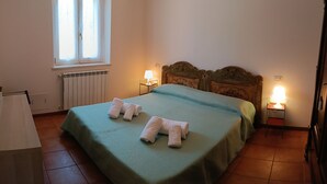 Een slaapkamer met een bed, twee bedlampjes, een raam en een radiator.