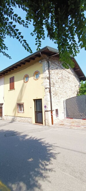 A building with a stone facade, a yellow exterior, and a metal gate.