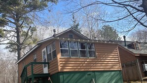 Une cabane en rondins avec une façade verte, un porche et une cheminée.