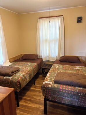 A room with two beds, a small table, and a window with curtains.