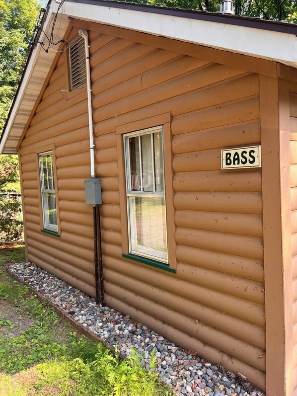A small wooden cabin with a 'BASS' sign, a window, and a utility box.