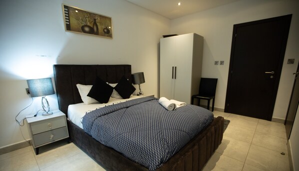 Une chambre à coucher avec un lit, des tables de chevet, une armoire et une porte.