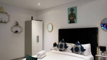 Ein modernes Hotelzimmer mit einem großen Bett, einem Schrank, einem runden Spiegel und einem Bild an der Wand.