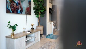 A modern kitchen with a built-in washing machine, a large potted plant, and a flat-screen TV mounted on the wall.