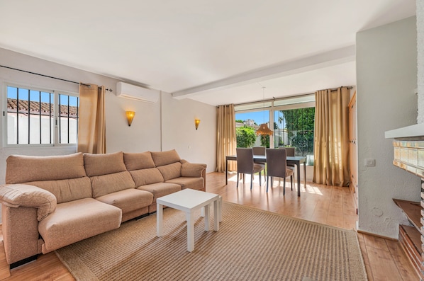 Una sala de estar moderna con un sofá, una mesa de comedor con sillas y vistas al exterior.