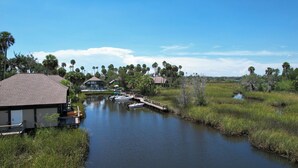 A riverside property with a dock, boats, and a house with a dock.