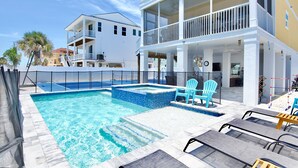 A pool area with lounge chairs and a two-story building with balconies.