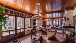 A spacious living room with wooden ceilings and large windows, a fireplace, and leather furniture.