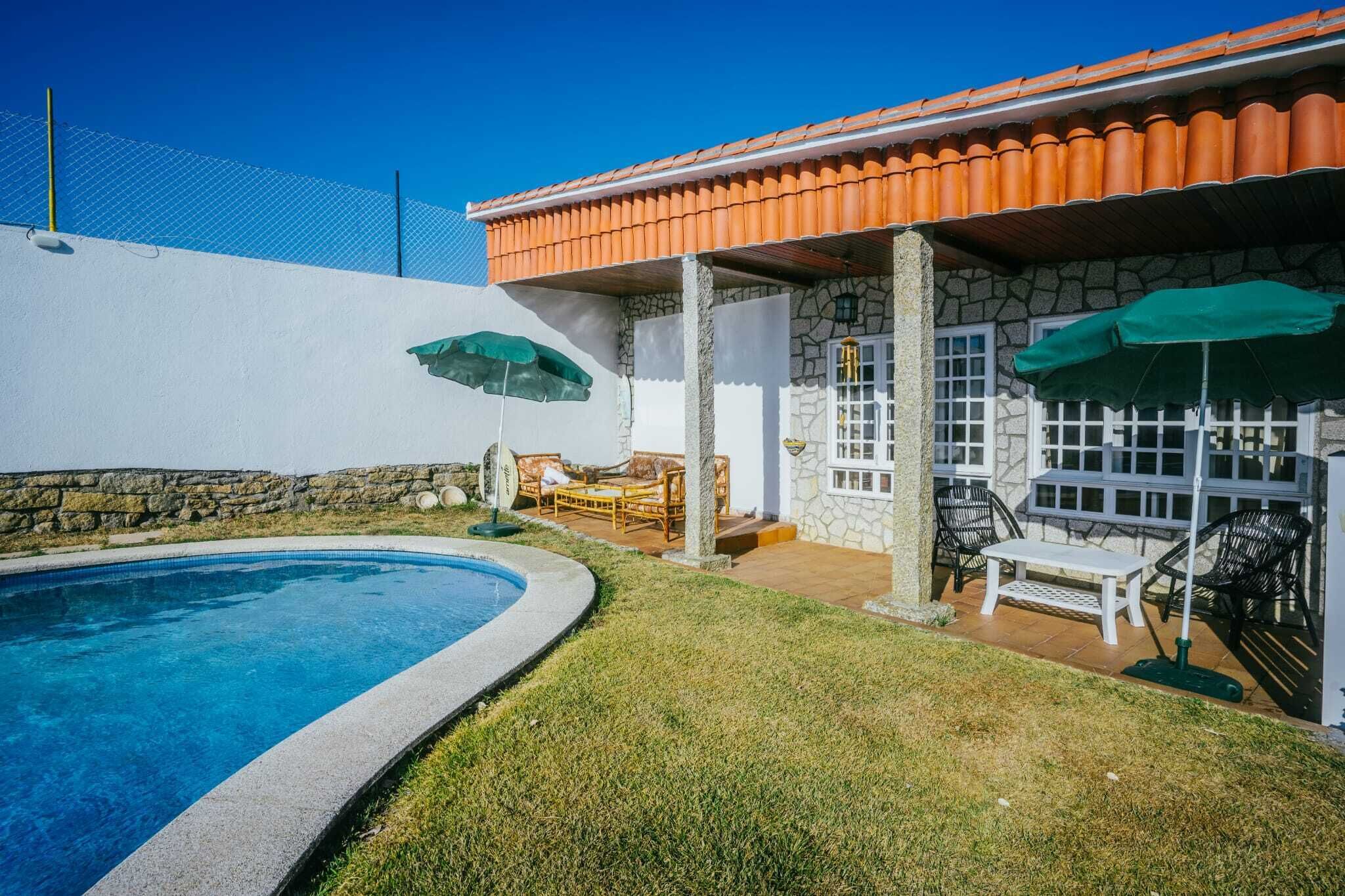 Un patio trasero con piscina, muros de piedra y mobiliario exterior.