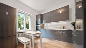 A modern kitchen with a built-in oven, a refrigerator, and a window providing a view of the outdoors. - 19 min to the center - 250 m² / 2,691 sq ft - top villa from 1923 - 4BR 3,5BA (Gräfelfing)