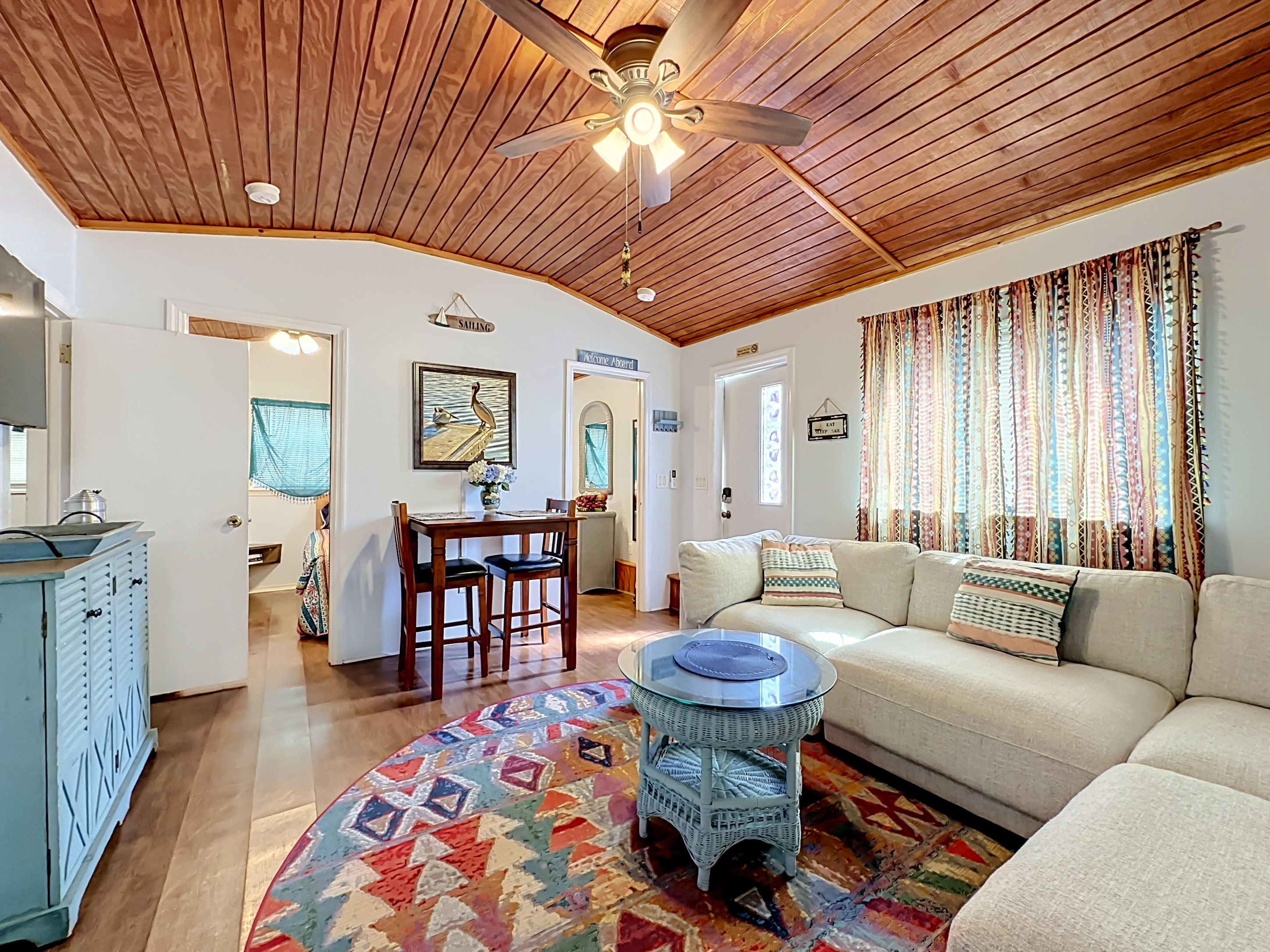 A living room with a wooden ceiling, a round coffee table, a sofa, and a patterned rug.