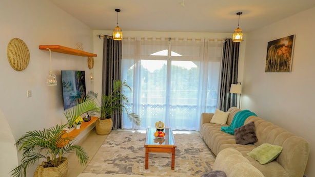 A living room with a sofa, a coffee table, and potted plants. - 2BR Apt, 6-Min Walk to Diani Beach, Kids Playground, Near Ukunda Airport. (Diani Beach)