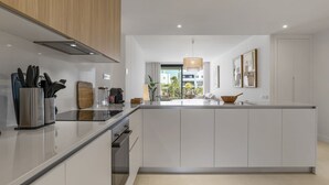 A modern kitchen with a central island, white cabinetry, and a view of the outdoor patio. - Lani | Terrace - pool - garden (Estepona)