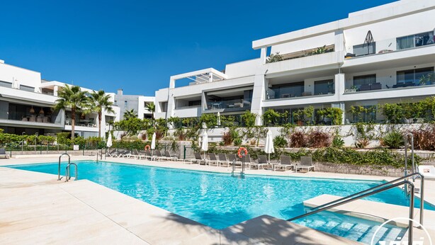 A modern hotel with a pool area, including lounge chairs and umbrellas, surrounded by greenery and white buildings. - Lani | Terrace - pool - garden (Estepona)