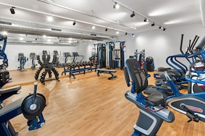 Ein Fitnessstudio mit verschiedenen Trainingsgeräten, darunter Laufbänder, Kraftgeräte und Kurzhanteln.