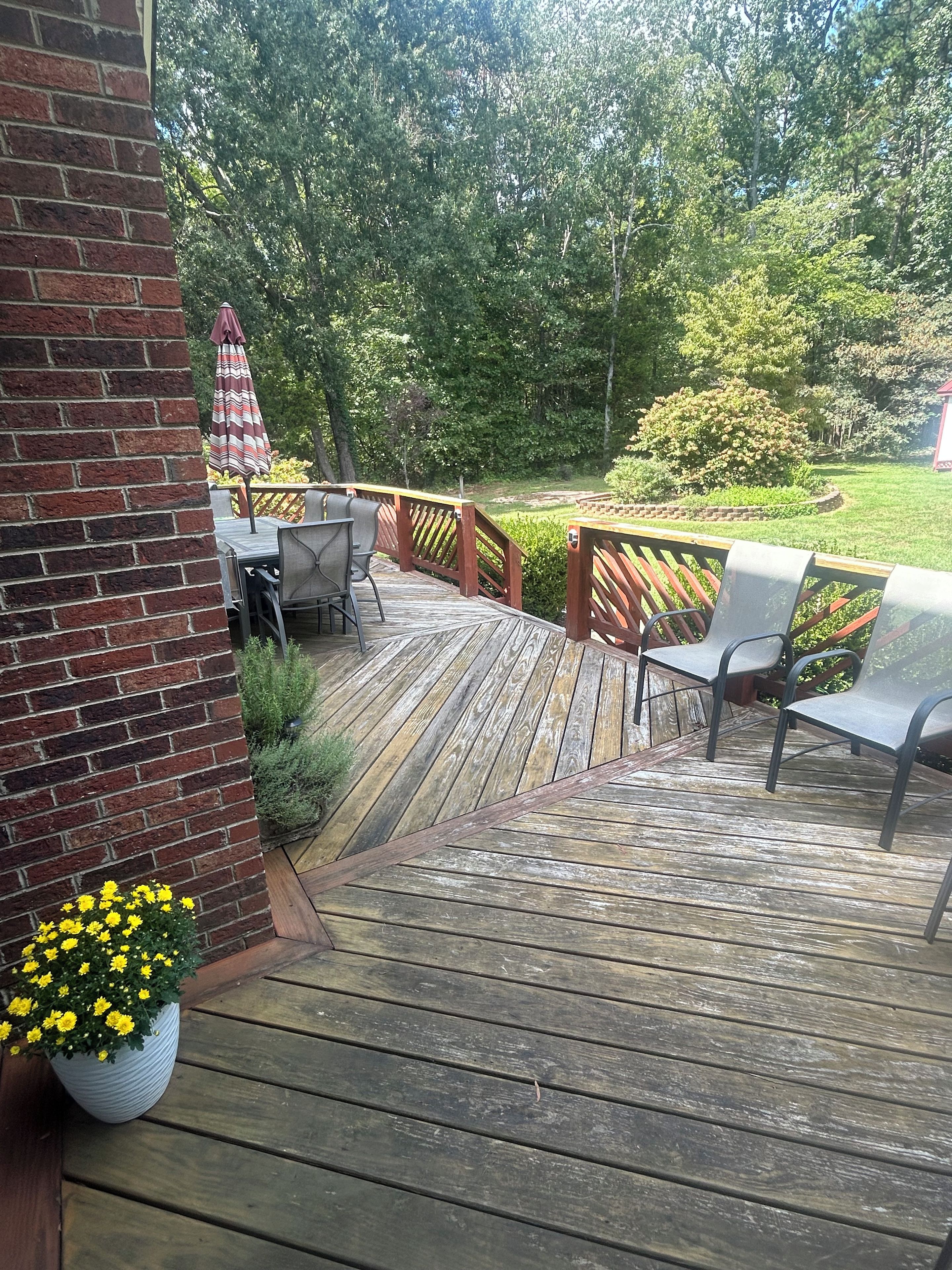 A wooden deck with outdoor furniture and a brick wall.