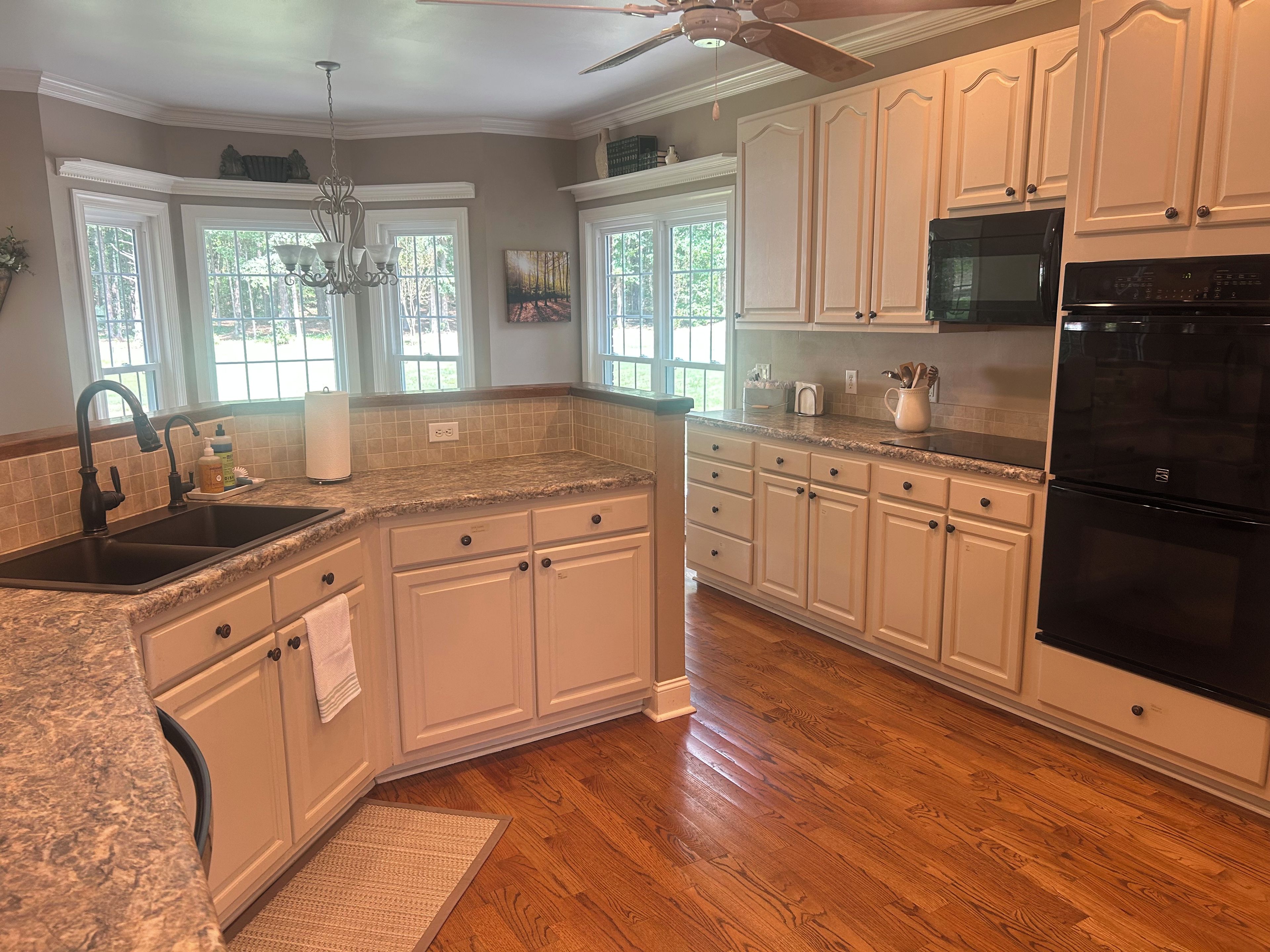 A kitchen with white cabinets, a black refrigerator, and a granite countertop.