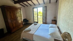 Een slaapkamer met een bed, een houten garderobe en een plafondventilator.