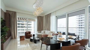 Uma área de refeições moderna com mesa de vidro, cadeiras de couro e um candelabro.