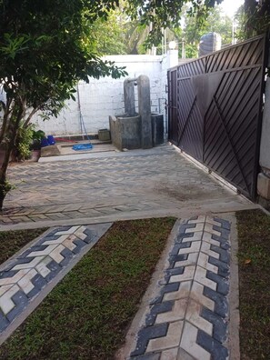 Une terrasse dallée avec un motif géométrique en carreaux, une porte en métal et un réservoir d’eau en arrière-plan.