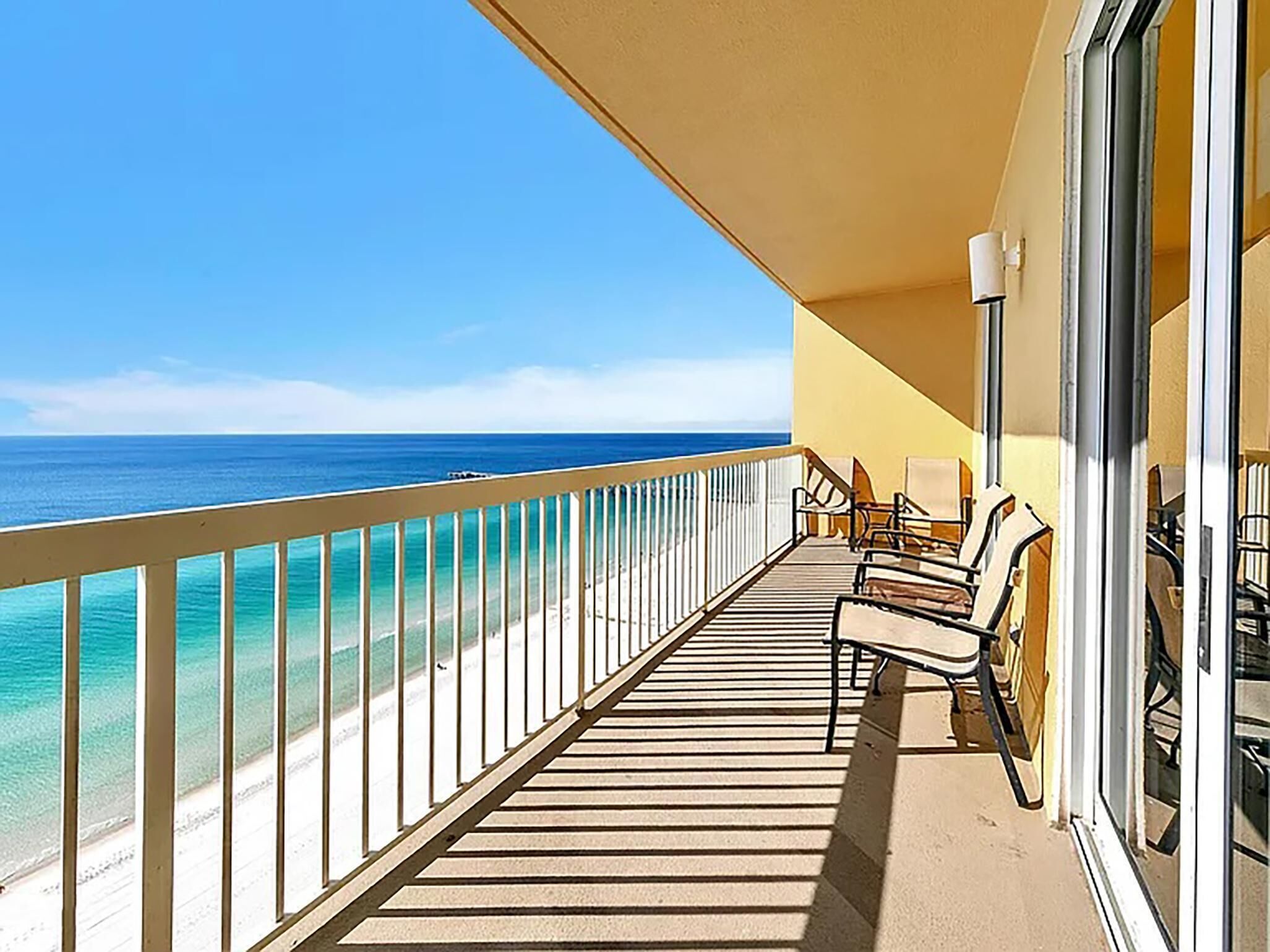 A balcony with a view of the ocean, equipped with outdoor furniture and a glass railing.