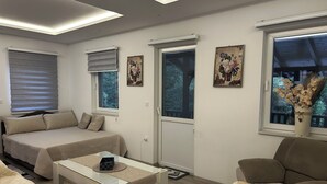 A modern living room with a sofa, a glass coffee table, a bed, and a door leading to another room. - Terrific villa with AC in charming Sarajevo (Sarajevo)