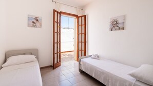 Une chambre avec deux lits, une fenêtre avec des rideaux et deux tableaux accrochés au mur.