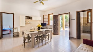 Un grand espace de vie comprenant un coin repas avec une table et des chaises, un ventilateur de plafond et un coin cuisine.