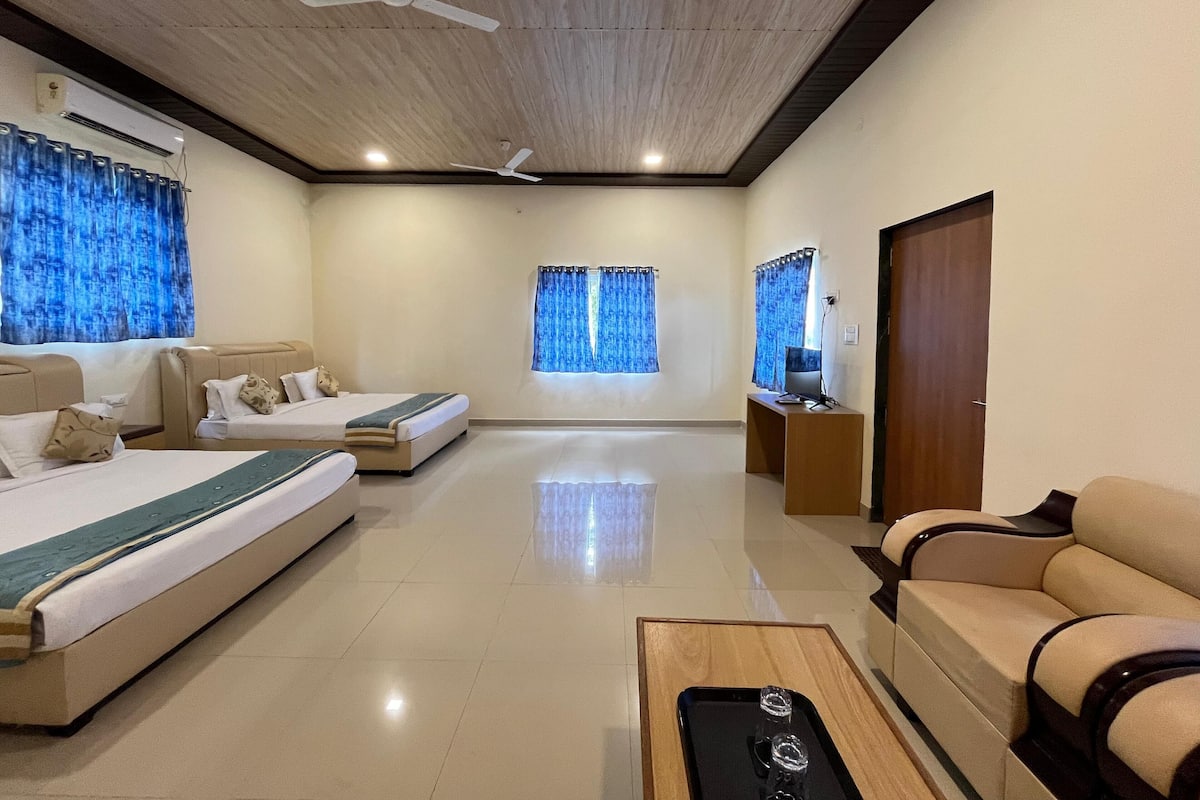 A hotel room with a bed, a sofa, a TV, and a ceiling fan.