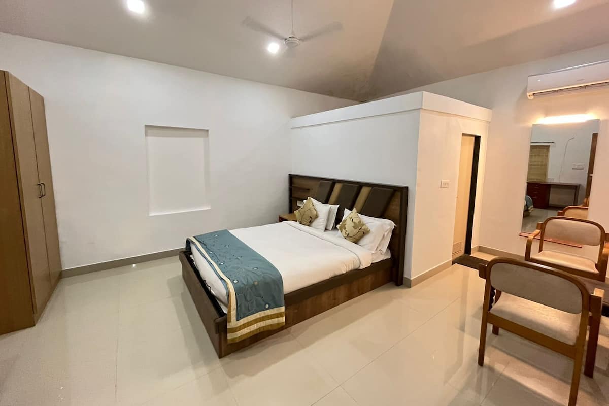 A bedroom with a bed, a chair, a wardrobe, and a ceiling fan.