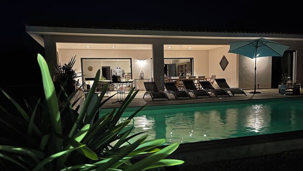 Ein Poolbereich mit Liegestühlen und einem Sonnenschirm, umgeben von einem modernen Gebäude mit Pool.