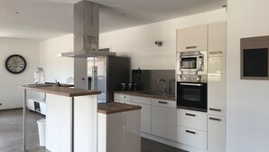 Eine moderne Küche mit Kochinsel, Edelstahlgeräten und weißen Schränken.