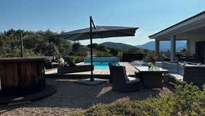 Ein Poolbereich mit Liegestühlen, einem Tisch und einem Sonnenschirm.
