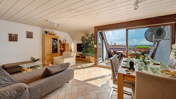 Ein modernes Wohnzimmer mit Sofa, Esstisch und Meerblick durch große Fenster.