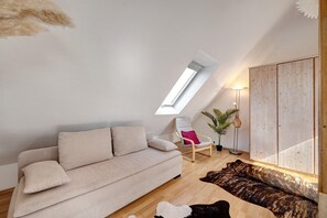 Una sala de estar moderna con un sofá, un sillón, un armario de madera, una lámpara de pie y un tragaluz.