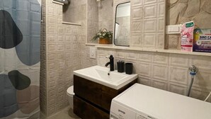 A modern bathroom with a built-in washing machine, a toilet, and a shower area. - Charming 1-bedroom apartment in delightful Split with AC (Split)