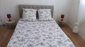 Une chambre à coucher avec un lit, deux tables de chevet et une fenêtre avec des rideaux.
