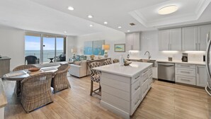 Una cocina moderna con una isla grande, armarios blancos y vistas al exterior.