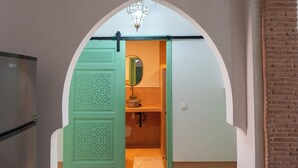 An arched doorway leading to a bathroom with a mirror and a towel on the floor. - Beldi Chic Appartment in Guéliz Marrakech – AC, Netflix, Zellige (Marrakesh)