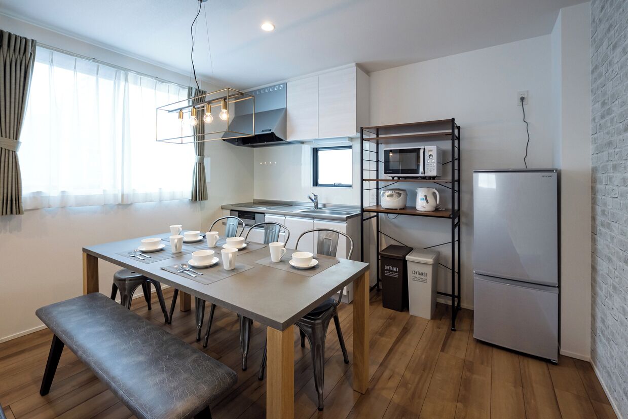 A modern kitchen with a dining table set for four, a built-in microwave, and a stainless steel refrigerator.