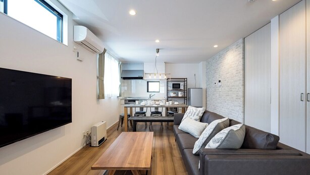 Una sala moderna con un televisor de pantalla plana, una mesa de centro de madera y un sofá gris con cojines estampados.
